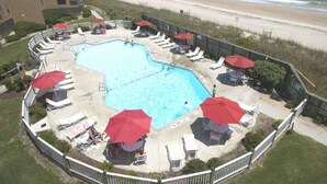 A rooftop pool with lounge chairs and umbrellas, overlooking a beach. - Oceanfront! Topsail Dunes Beachfront Condo with Pool and Balcony (North Topsail Beach)