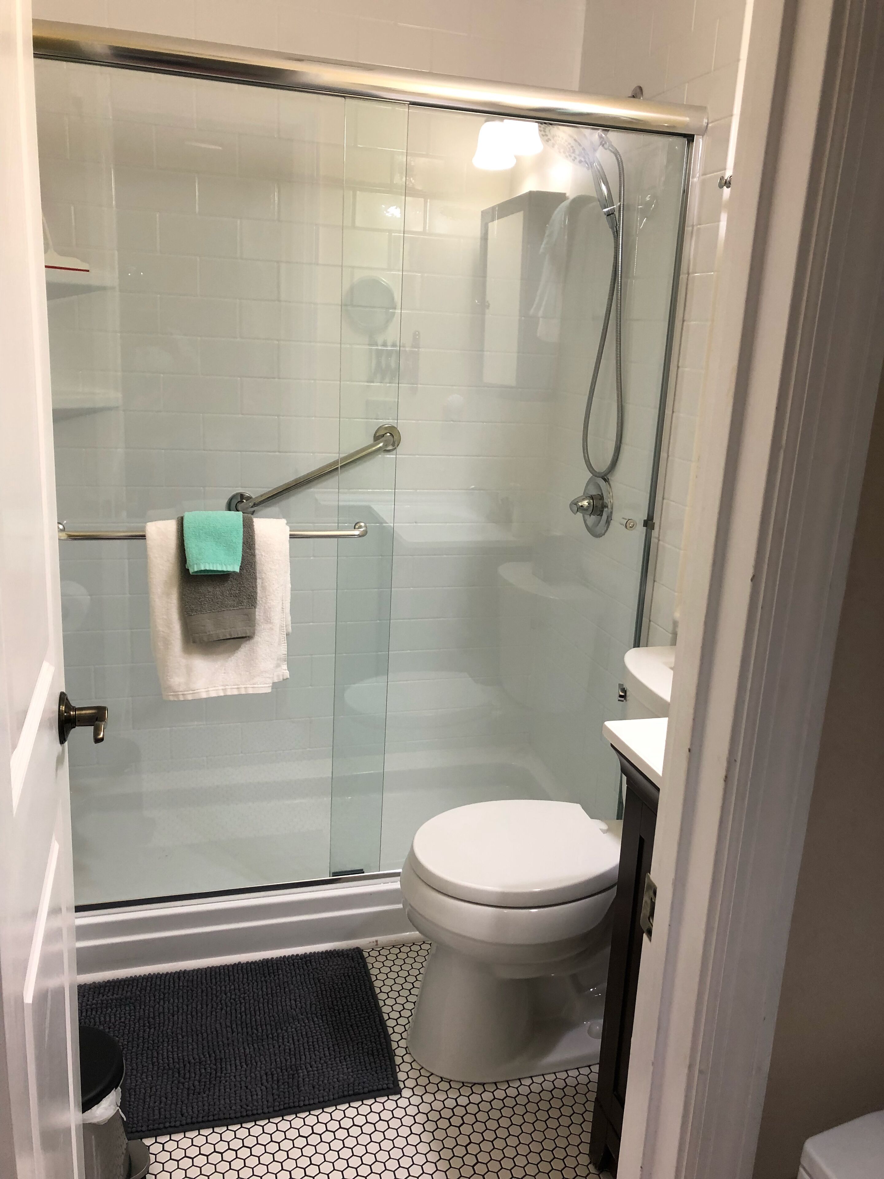 A bathroom with a glass shower enclosure, a white toilet, and a small sink.