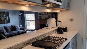 Une cuisine moderne dotée d’un îlot central, d’un four à micro-ondes encastré et d’une cuisinière à gaz.
