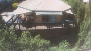 A building with a large, flat roof and a covered outdoor area with a railing. - Beach Place-family friendly (Lakes Entrance)