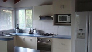 A kitchen with white cabinets, a stove, a microwave, and a refrigerator. - Beach Place-family friendly (Lakes Entrance)