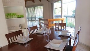 A dining area with a wooden table set for four, surrounded by chairs. - Beach Place-family friendly (Lakes Entrance)