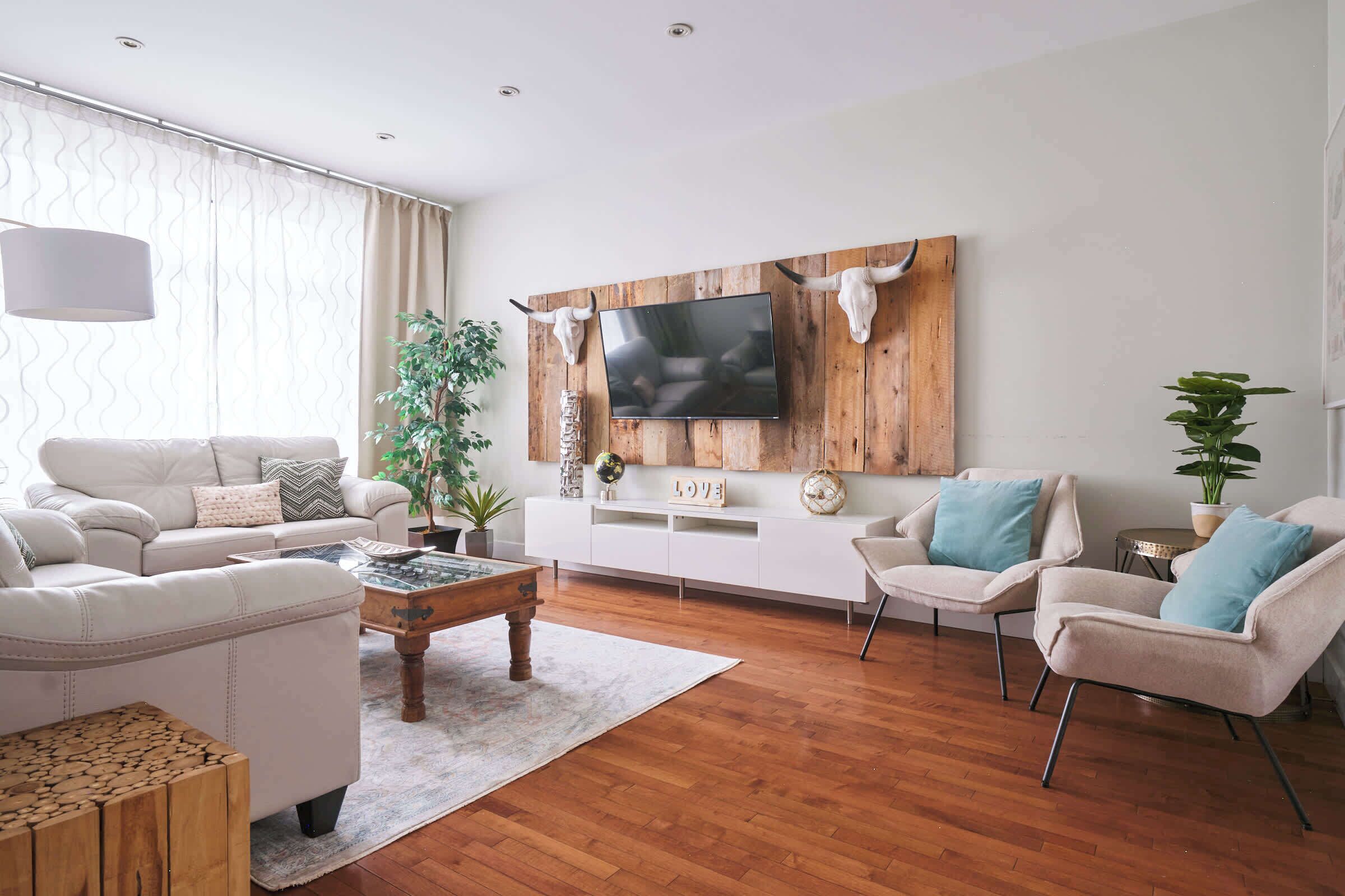 A modern living room with a wooden TV stand, white sofas, and a coffee table.