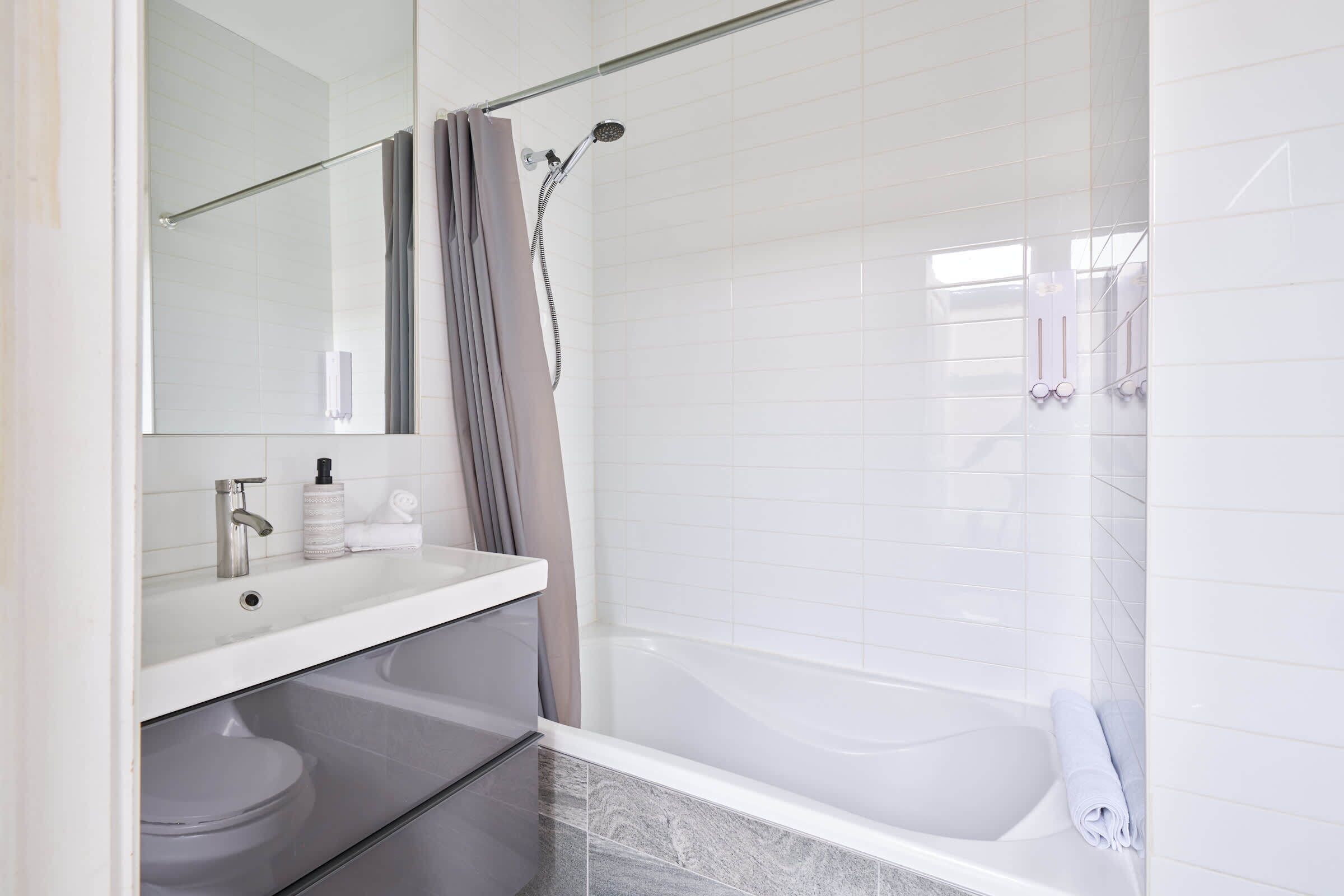 Un baño moderno con bañera, ducha, inodoro y tocador con espejo.