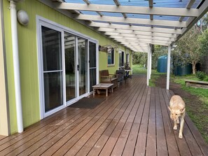A wooden deck with a covered patio area, sliding glass doors, and outdoor furniture. - Dog friendly close to beach/shops, trampoline, hot outside shower, NBN Wifi (Sandy Point)