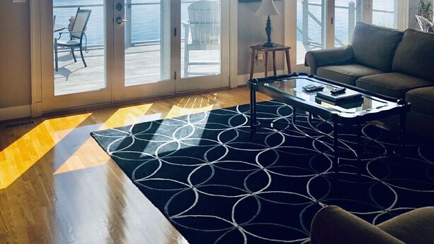 Een ruime woonkamer met een groot raam, een plafondventilator en een kamerbreed tapijt.