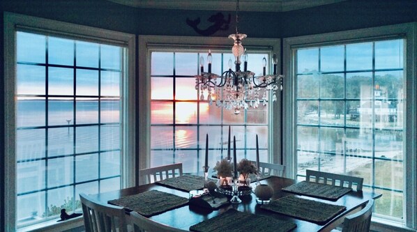 Enjoy meals with a view of the water from this dining area featuring a chandelier, round table, and candles.