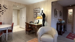 A dining area with a round table, chairs, a desk with a lamp, and framed pictures on the wall. - Luxury Apartment in Great Location. Come and be Parisian for a week! (Boulogne-Billancourt)