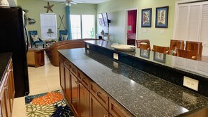 A kitchen with a granite countertop, wooden cabinets, and a ceiling fan. - Bubbles Up. Ocean View Corner Unit in Coconut Grove. North Myrtle Beach, SC (North Myrtle Beach)