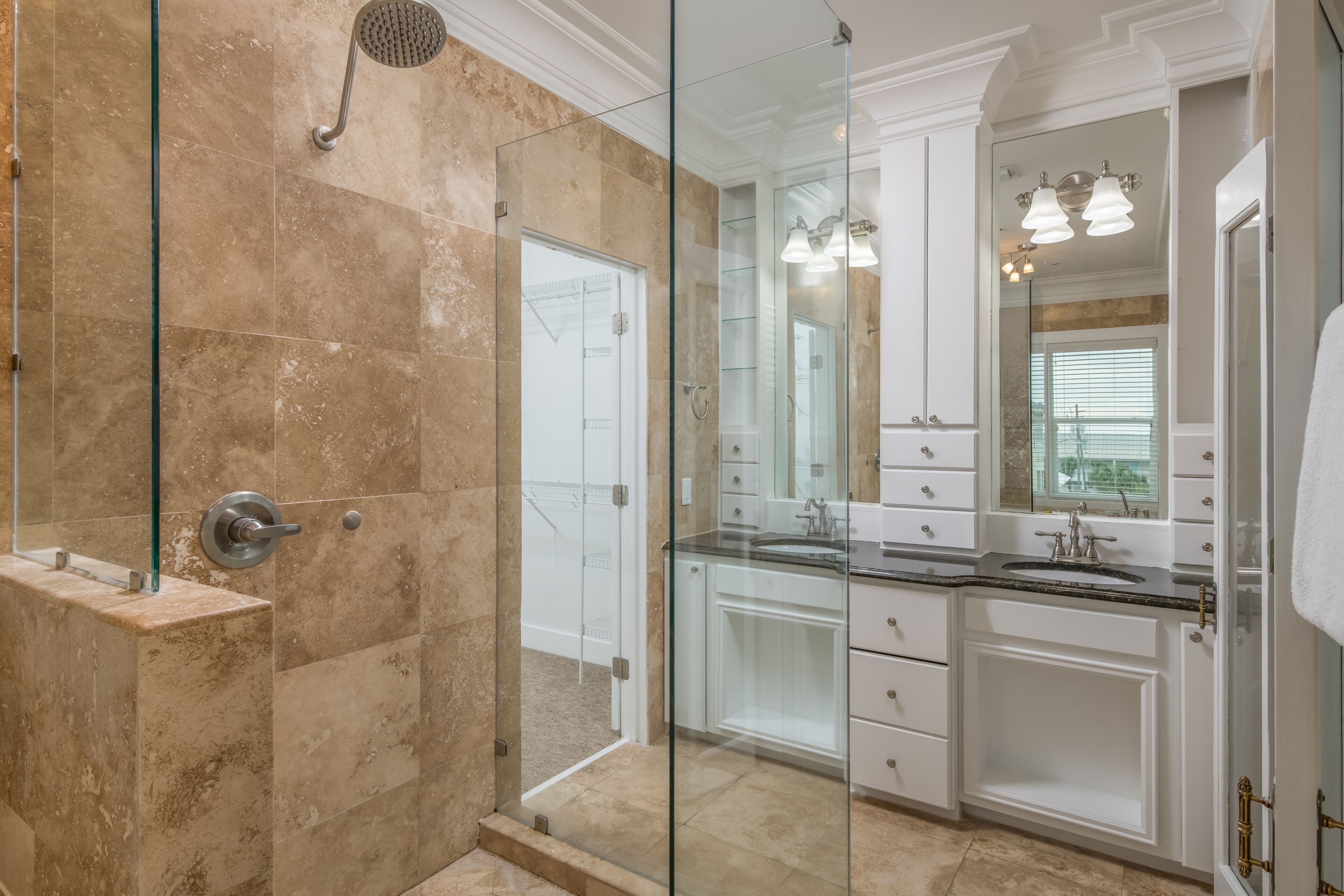 A modern bathroom with a glass-enclosed shower, white cabinetry, and a large mirror.