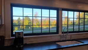 A kitchen with a large window overlooking a scenic landscape.