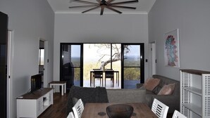 Un salon moderne doté d’une grande porte-fenêtre coulissante qui donne sur une terrasse offrant une vue panoramique.