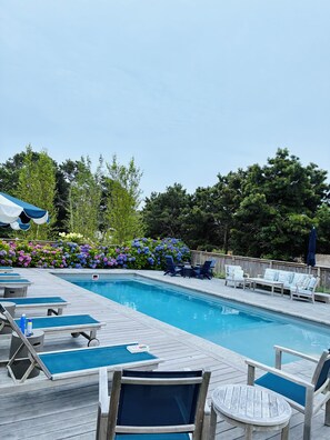 A swimming pool with lounge chairs and a wooden deck.