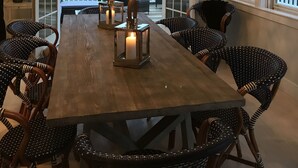 A dining area with a wooden table, wicker chairs, and a hanging light fixture.