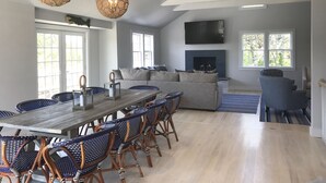 A spacious living area with a large sofa, a dining table with chairs, and a fireplace.