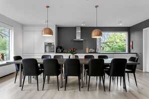 A modern kitchen with a large island, black chairs, and pendant lighting.