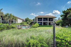 A modern two-story building with a flat roof and a swimming pool in the background.