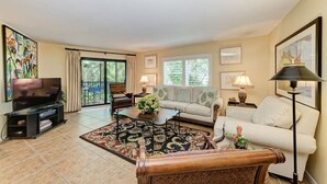A living room with a TV, sofa, coffee table, and a patterned rug.