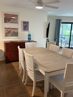 Un comedor con una mesa y sillas, un armario de madera y carteles enmarcados en la pared.