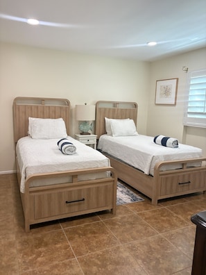 Un dormitorio con dos camas, una mesita de noche, una lámpara y un cuadro en la pared.