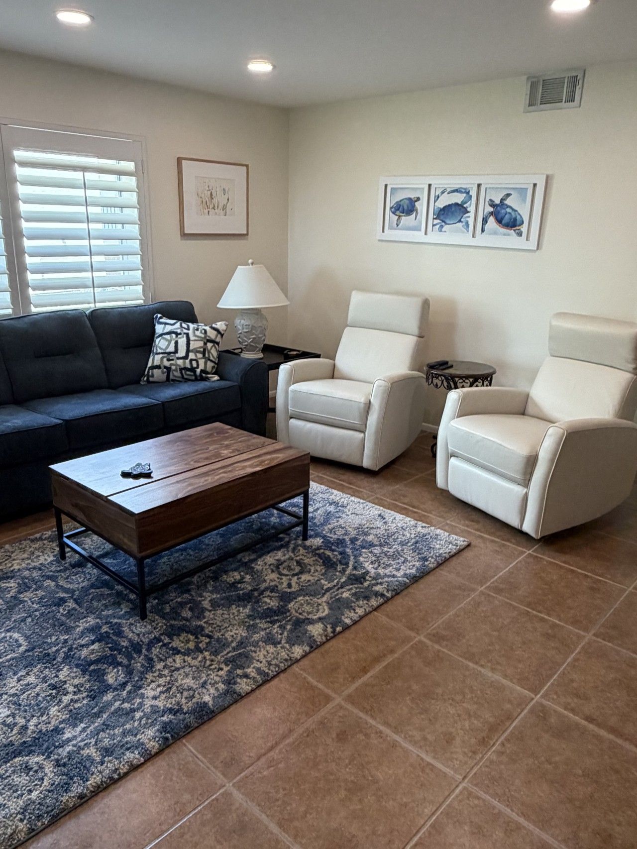 A living room with a sofa, two armchairs, a coffee table, a lamp, and a rug.
