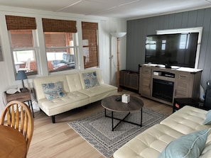 Uma sala de estar com sofá, mesa de centro, televisão e lareira.
