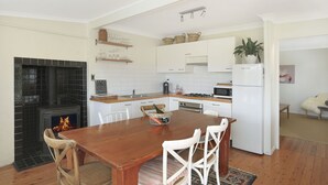 A kitchen with a central island, white cabinets, a stove, and a refrigerator. - Twin Oaks Cottage - Fitzroy Falls  (Fitzroy Falls)