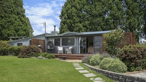A modern house with a patio, stone pathway, and lush greenery. - Twin Oaks Cottage - Fitzroy Falls  (Fitzroy Falls)