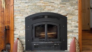 Una chimenea de piedra con un arco negro y un repisa de madera.