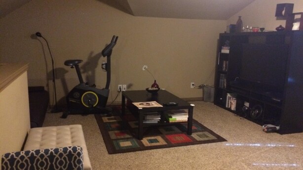 A living room with a sofa, a coffee table, an exercise bike, a TV, and a bookshelf. - Joe Pool Lake Resort Style-Upscale Gorgeous Home!!! (Grand Prairie)