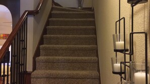 A carpeted staircase with a wooden handrail and a wall-mounted candle holder with multiple candles. - Joe Pool Lake Resort Style-Upscale Gorgeous Home!!! (Grand Prairie)