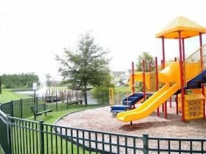 Kids can play on the slide and climbing structure within the enclosed playground area.