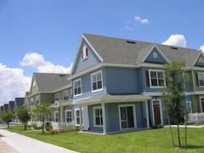Stylish townhouses with gabled roofs and front porches, set in a charming neighborhood with manicured lawns and mature trees.