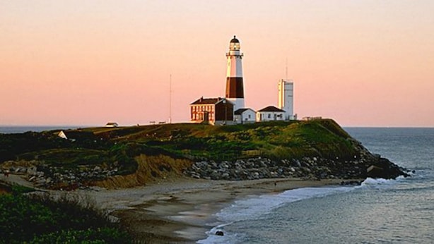 A lighthouse on a grassy island with a building nearby, overlooking the sea. - Ditch Plains - Walk to Ocean Beach - New Kitchen, Bath, & Bedrooms (Montauk)