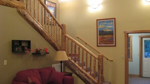 A staircase with wooden railings, a red couch, and a framed picture of a mountain landscape. - Wonderful Winter Escape with Mountain views in Forest-like setting (Burney)