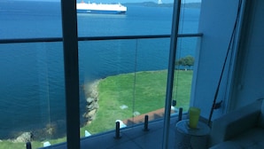 Blick von einem Balkon auf ein Gewässer, im Hintergrund ein großes Schiff.