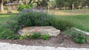A garden with a stone centerpiece, surrounded by various plants and flowers.
