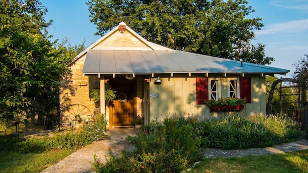 A small, single-story building with a sloped roof, a wooden door, and a welcome sign.