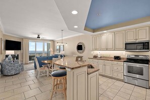 A modern kitchen with a large island, stainless steel appliances, and a view to the outside.