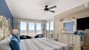 Ein Schlafzimmer mit Bett, Kommode, Fernseher und einem Balkon mit Blick.