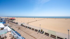 Eine Promenade mit Bänken und einem Strand im Hintergrund.