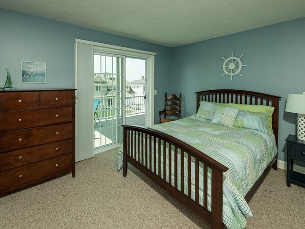Quarto com cama, penteadeira e vista através de uma porta de correr.