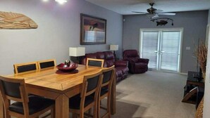 A dining area with a wooden table and chairs, a red bowl, and a ceiling fan.