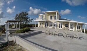 Un bâtiment à deux étages doté d’un patio couvert, d’un espace extérieur aménagé pour s’asseoir et offrant une vue sur le paysage environnant.