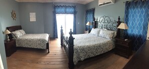 Une chambre avec deux lits, un plancher en bois et une fenêtre avec des rideaux.