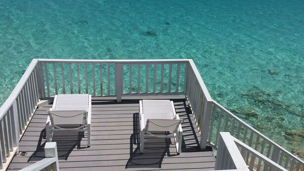 A wooden deck with two white sun loungers and a railing overlooking clear turquoise water. - "The Cut Pearl" - Stunning Private Beachfront/Oceanfront Villa On Little Exuma (Forbes Hill)