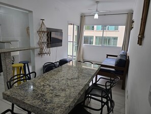 A modern kitchen with a granite countertop, a dining area with a long table, and a small sofa.