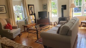 Uma sala de estar com sofá, poltrona, televisão, lareira e piso de madeira.