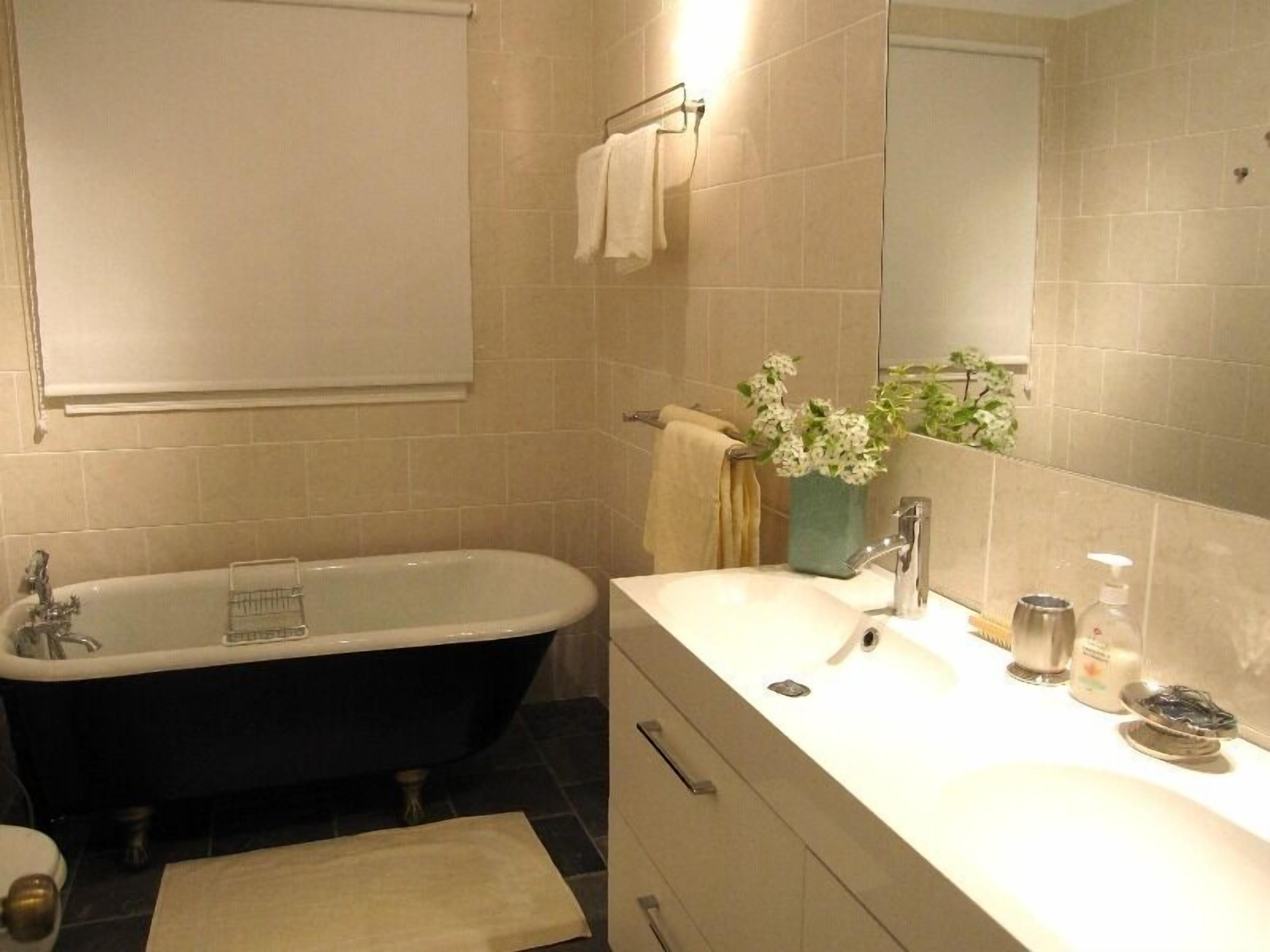 Un baño con bañera, lavamanos, espejo y perchero.