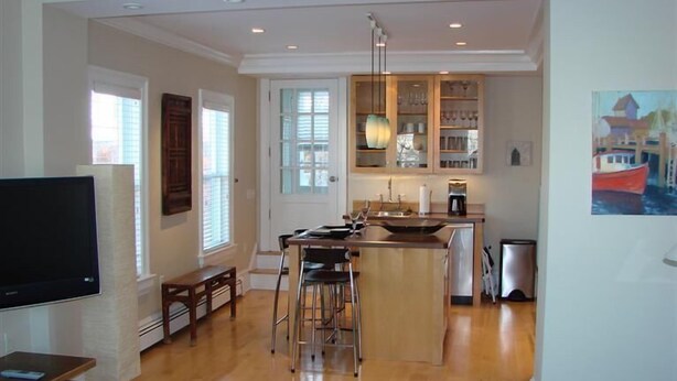 Un amplio salón con isla de cocina, una mesa de comedor y un televisor.